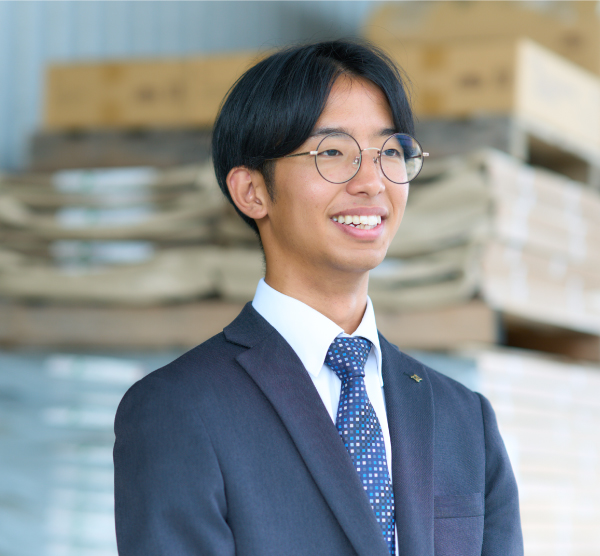 自社倉庫の前で微笑む先輩社員